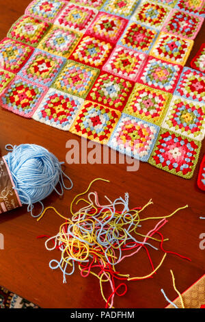 Vivacemente colorato granny square lana per bambini coperta, tradizionale fatta a mano a uncinetto home artigianato, con sfera di lana blu e thread Foto Stock