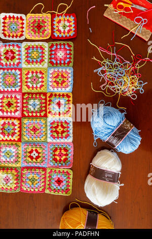 Pallini di lana per un luminoso color pastello granny square lana per bambini coperta, tradizionale fatta a mano a uncinetto home artigianato e tagliare le filettature Foto Stock