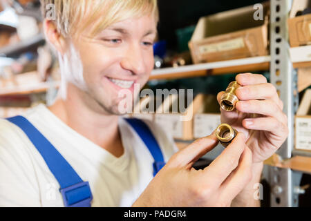 Close-up delle mani di un lavoratore di contenimento tubo due accessori di montaggio Foto Stock