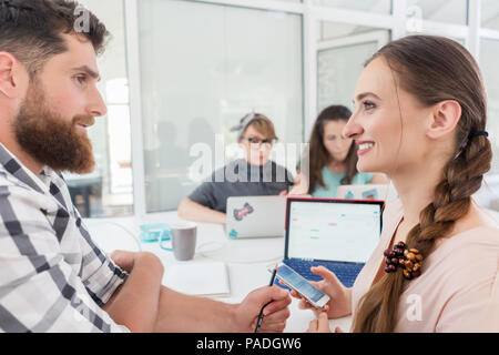 Creative freelance femmina sorridente al co-lavoratore Foto Stock