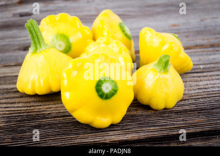 Piccole dimensioni patty pan patisson squash closeup Sfondo legno Foto Stock