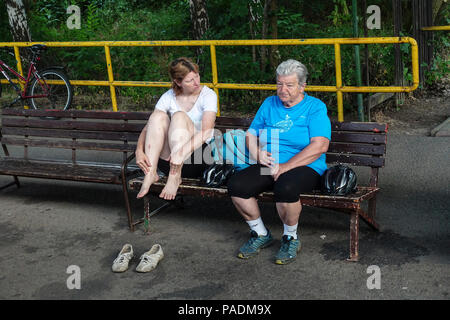 Due motociclisti donne sul binario della stazione ferroviaria stanno aspettando il treno, piccola comunicazione intergenerazionale, Repubblica Ceca seduta sulla panchina Foto Stock