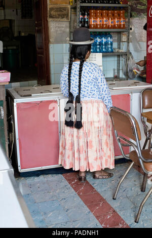 L Aymara donna con lunghe trecce, indossando la peste Bowler cappello in attesa presso la gelateria. Ottobre 13,2012 - Chulumani, Sud Yungas, Bolivia Foto Stock