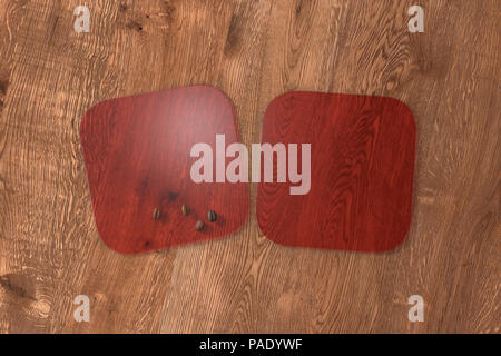 Due quadrati rosso trasparente montagne russe e i chicchi di caffè su uno sfondo di legno. 3d illustrazione Foto Stock