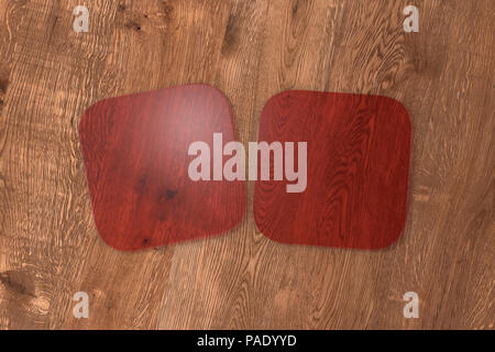 Due quadrati rosso trasparente coasters su uno sfondo di legno. 3d illustrazione Foto Stock
