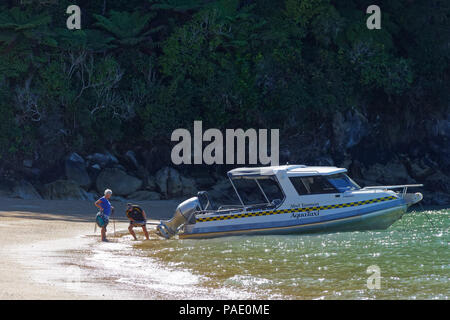 Taxi d'acqua raccolta di un passeggero fuori dalla spiaggia, il Parco Nazionale Abel Tasman, Nuova Zelanda Foto Stock