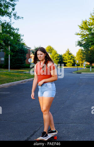 Carino Il giovane skater girl skateboard su attiva di teen girl skateboard equitazione sulla strada, godendo di una bella giornata. Foto Stock