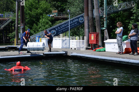 Ron Hilburger, Guardia costiera, ausiliario e il Tenente j. g. Adam Birch, nave statunitense ispettore di sicurezza marina Portland unità, dimostrare come distribuire una zattera gonfiabile canister per membri del Washington Homeland Security Tavola Rotonda nel fiume Willamette in bacini marini di unità di sicurezza Portland, Ore., 16 luglio 2018. Zattere di salvataggio sono uno dei tanti necessari elementi di sicurezza su tutti i dipendenti degli Stati Uniti e stranieri di navi commerciali. Stati Uniti Coast Guard foto di Sottufficiali di terza classe Trevor Lilburn. Foto Stock