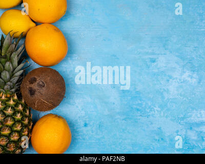 Arance, ananas e noce di cocco su sfondo blu Foto Stock