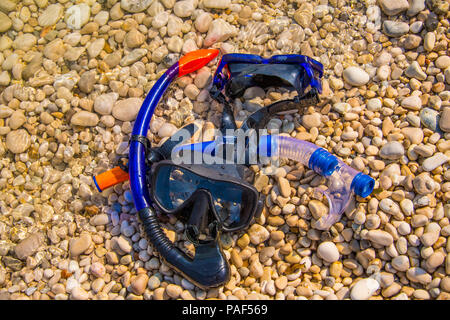 Maschere per lo snorkeling giacente su di una spiaggia di ciottoli. La vacanza estiva concept Foto Stock