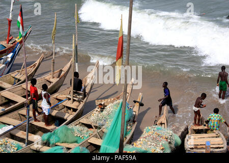 Gli adolescenti africani seduti sulla panchina canoe guardando gli altri la balneazione in Oceano Atlantico - Cape Coast, in Ghana Foto Stock