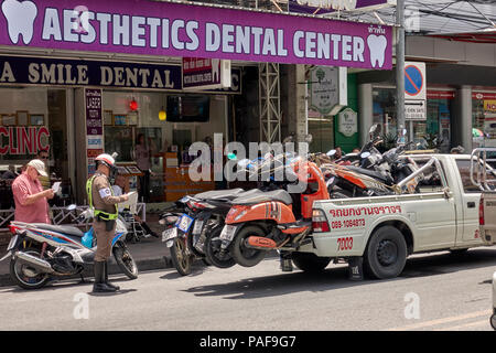 Thailandia polizia stradale che rilascia un biglietto per motocicli parcheggiati illegalmente che devono essere impattati in attesa di pagamento di multa. Foto Stock