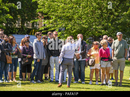 Tour guida per spiegare la storia dell'area di un gruppo di turisti fuori Buckingham Palace a Londra Foto Stock