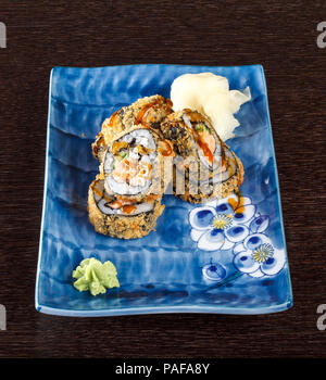 Fritti caldi sushi rotoli su una piastra con salmone e cetrioli su un tavolo di legno. Foto Stock