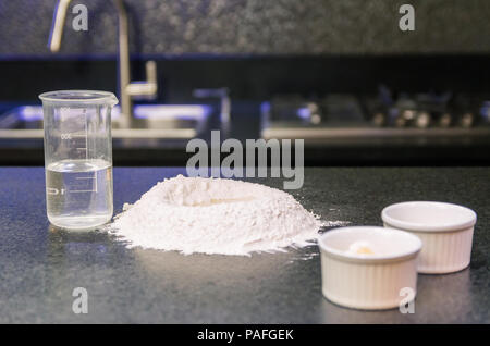 Cumulo di farina di grano sulla sommità del granito nero del tavolo, preparazione di impasto per pizza. Foto Stock