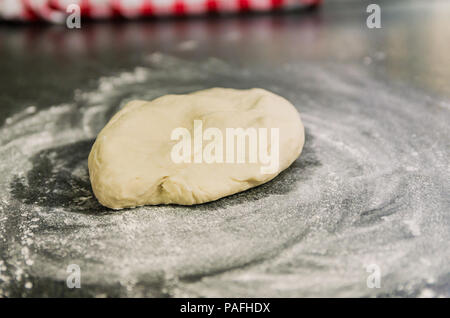 Cumulo di farina di grano sulla sommità del granito nero del tavolo, preparazione di impasto per pizza. Foto Stock