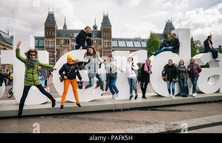 Amsterdam, Paesi Bassi - Aprile 27,2017: Diversità turisti interagire con enormi lettere I Amsterdam - simbolo della città. Foto Stock