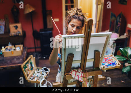 Piscina colpo di professional artista femminile dipinto su tela in studio con piante. Foto Stock