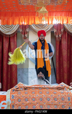 Un sacerdote Sikh, un Granthi, lettura Sri Guru Granth Sahib, che è il libro santo in sikhismo. In Richmond Hill Queens, a New York. Foto Stock