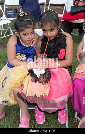 Carino Sikh sorelle che condividono una bevanda fredda in un giorno di estate a i sikh Gurmat giochi a Smokey Park nel Sud di Richmond Hill, Queens, a New York. Foto Stock