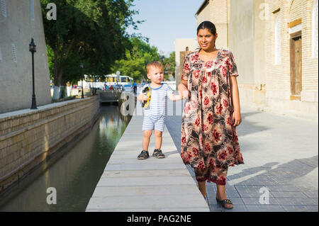 BUKHARA, UZBEKISTAN - 6 giugno 2011: Non identificato donna uzbeka passa per una passeggiata con il suo bambino in Uzbekistan, giu 6, 2011. Il 81% delle persone in Uzbekistan belo Foto Stock