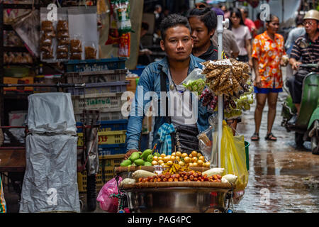 Bangkok, Tailandia - 1 Maggio 2018 :: il giovane uomo che porta un carrello pieno di cibo di strada per le strade di Bangkok Foto Stock