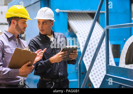 Lavoratori in fabbrica a discutere gli uni con gli altri in fabbrica Foto Stock