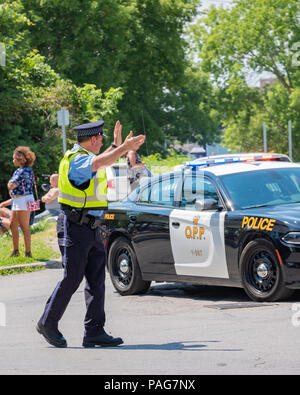 Ausiliario per un funzionario di polizia dirige il traffico su una strada trafficata durante un evento in Orillia Ontario. Foto Stock