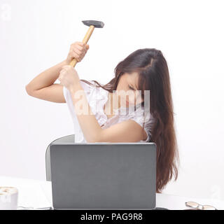 Young business woman smashing un laptop seduto dietro una scrivania. Foto Stock