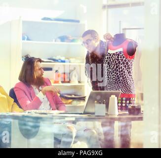 Vista da dietro un vetro.designer di moda a discutere di nuovi disegni di vestiti Foto Stock