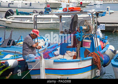 Pescatore sul pescatore in barca a riparare le reti da pesca Marina Grande, isola di Procida, il Golfo di Napoli, Italia Foto Stock