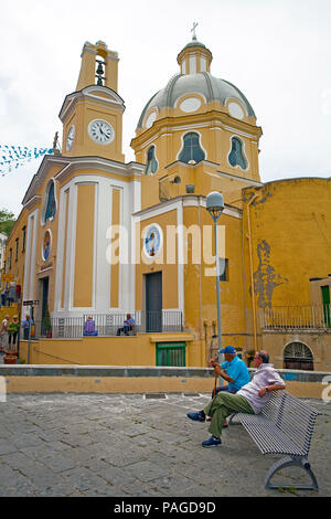 Gli uomini locali seduta su una panchina di fronte alla Chiesa della Madonna delle Grazie a Piazza dei Martiri, Procida, Golfo di Napoli, Italia Foto Stock