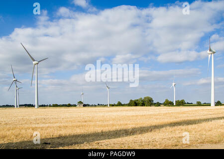 Fattoria eolica turbine, campo di grano, cielo azzurro, soffici nuvole verdi alberi in background. Six Hills nr Loughborough Leicestershire England Regno Unito. Foto Stock