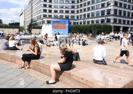 Londra. Regno Unito. Il 23 luglio 2018. Città i lavoratori godono di loro lunchbreak in estate il sole in Cabot Square, canry Wharf con temperature attese per raggiungere 35C di questa settimana e la Met Office emette un Ambra avviso meteo per le parti della Gran Bretagna colpita dall'attuale ondata di caldo Credito: amer ghazzal/Alamy Live News Foto Stock