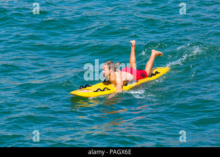 Bournemouth Dorset, Regno Unito. Il 23 luglio 2018. Regno Unito: meteo canicola continua Come temperature aumento su una cocente sole e caldo giorno a Bournemouth spiagge con un cielo azzurro e sole ininterrotta. Sunseekers in testa al mare a prendere il sole. RNLI Lifeguard surf sulla tavola da surf. Credito: Carolyn Jenkins/Alamy Live News Foto Stock