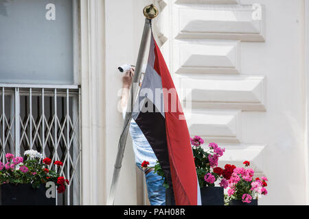 Londra, Regno Unito. 23 Luglio, 2018. Un uomo regola di una videocamera di sorveglianza dietro una bandiera irachena al di fuori dell'Ambasciata irachena. Credito: Mark Kerrison/Alamy Live News Foto Stock