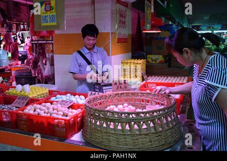 GUANGZHOU - CINA - CIRCA NEL MAGGIO 2018: una donna sceglie le uova nel mercato. Foto Stock