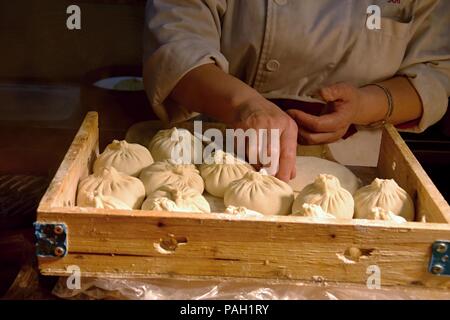 Una donna rende lievito gnocchi Cinesi 'bao zi' ripiene di carne e verdure. Foto Stock