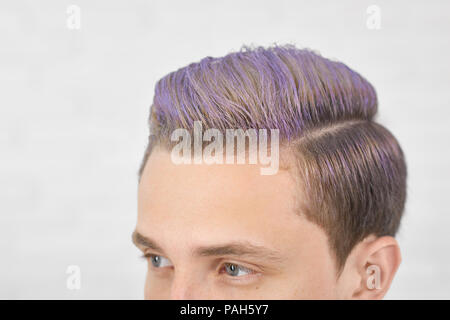 Foto ritagliata del giovane ragazzo con tonico per capelli lilla guardando in avanti. Avendo una perfetta copricapo, moderni, eleganti e alla moda. Modello maschile aventi grandi occhi blu, becchi dritti, piccole orecchie. Sfondo bianco. Foto Stock