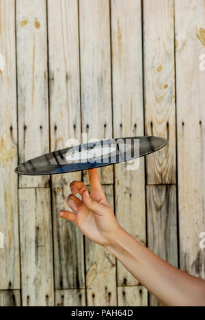 Femmina di mano che tiene il record di vinile su sfondo di legno Foto Stock