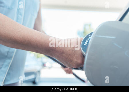 Close-up della mano di una donna senior il riempimento del serbatoio di gas della sua automobile Foto Stock