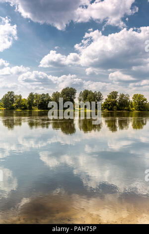 Pigre giornate estive a banca di fiume. Linea di alberi sul lato opposto alla banca fa simmetria Foto Stock