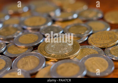 Pila di monete messicano in medio su una tavola di legno suggerendo una buona economia e abbondanza Foto Stock