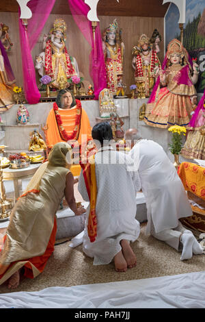 Una donna e due pandits condurre un servizio all'altare a Milano Mandir Hindu Temple in Sud Ozone Park, Queens, a New York. Foto Stock