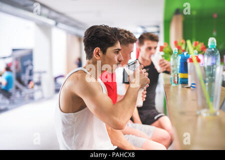 Uomini in palestra seduta e bicchieri di contenimento della bevanda di proteina. Foto Stock