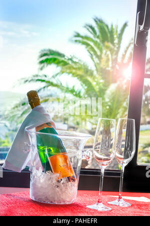 Champagne francese Luxury Hotel Villa Vacanza celebrazione Arrivo Veuve Clicquot vino spumante raffreddamento sul ghiaccio dalla finestra aperta al tramonto con esotici vista Palm tree view Foto Stock