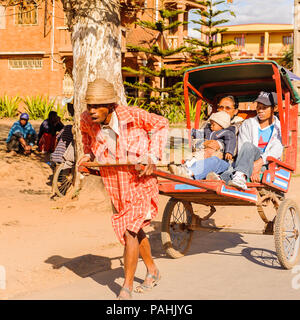 ANTANANARIVO, MADAGASCAR - Giugno 29, 2011: Madagascar non identificato uomo porta un carrello di trasporto con la madre e i bambini. Persone in Madagascar Foto Stock