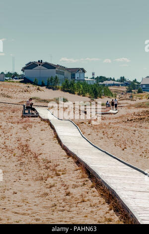 L'uomo adegua la sua macchina fotografica su un banco da boardwalk in Kalajoki, Finlandia. Le persone sono godendo di una calda giornata estiva a questa famosa spiaggia. Foto Stock