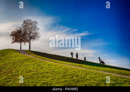 Felice famiglia giovane facendo una passeggiata nel parco con un bambino in un passeggino Foto Stock