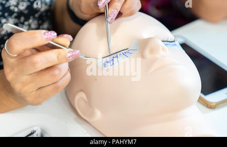 Formazione di base per costruire le ciglia su un manichino di silicone. Lavorare con pinzette, close up Foto Stock